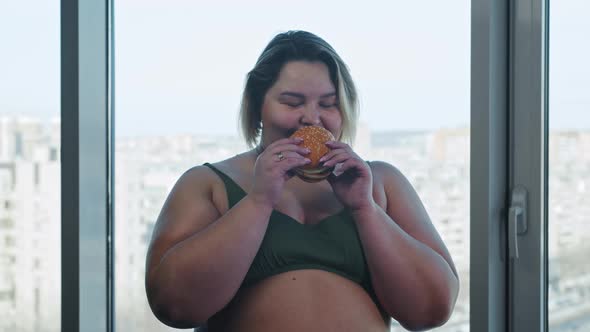 Smiling Overweight Woman Holding a Burger and Eating It  Body Positivity and Feminism