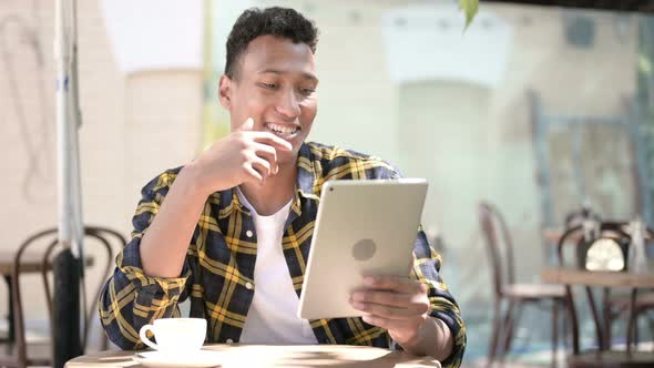 Video Chat on Tablet By Young African Man, Outdoor Cafe