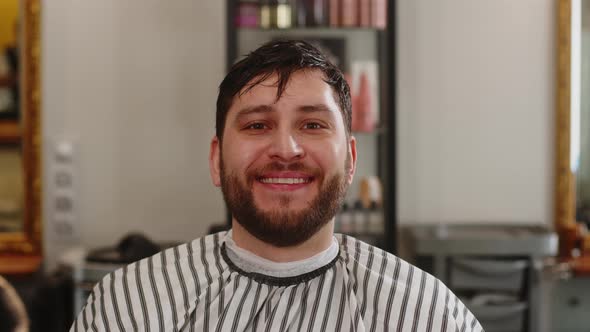Handsome Young Happy Man Smiling After Haircut While Sitting in Chair in Barbershop