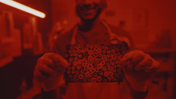 Photographer Holding Printed Photo in Darkroom