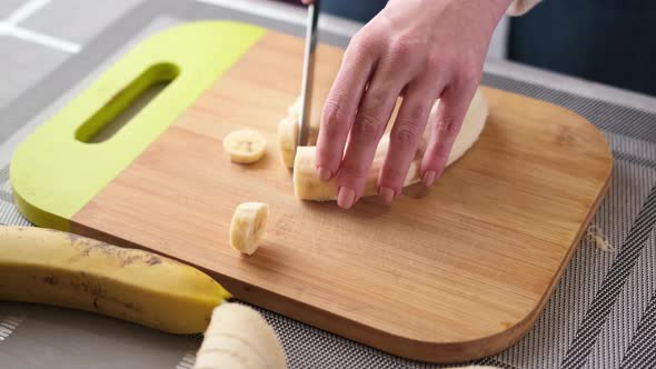 Woman Slicing the Yellow Banana on Wooden Cutting Board for Cake Filling