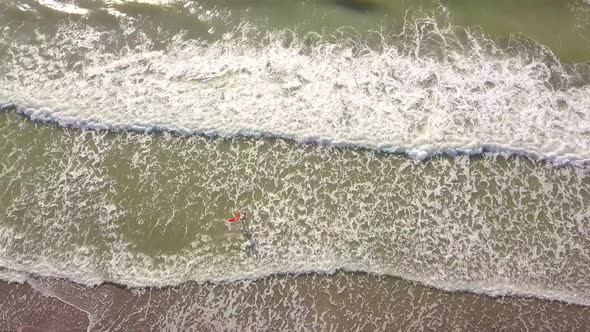 shooting from a drone, a woman enters the sea, and rejoices. happiness.