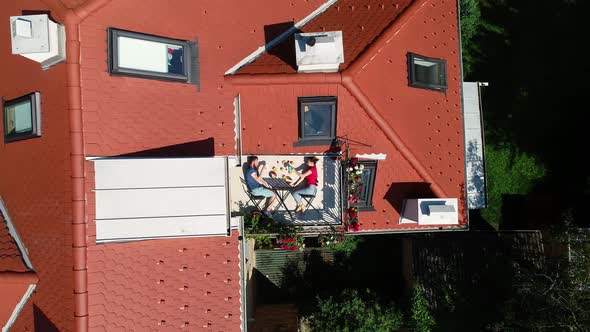 Aerial view of couple having breakfast on roof terrace.