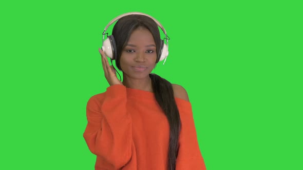 Young African American Woman with Headphones Listening and Grooving To Music on a Green Screen