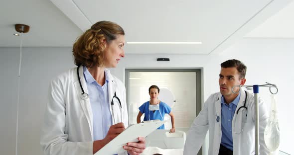 Doctors discussing over medical report while pushing emergency stretcher bed