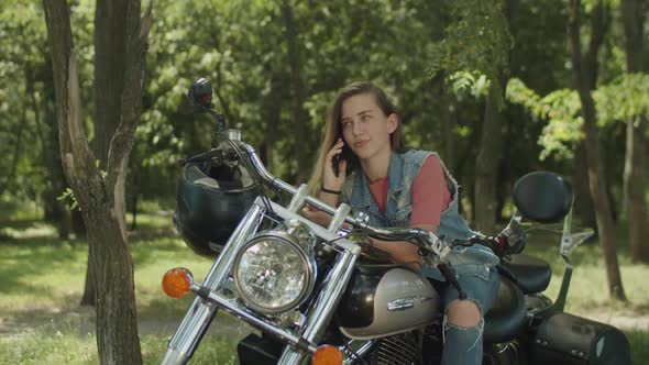 Cute Girl Talking on Phone Leaning on Motorbike