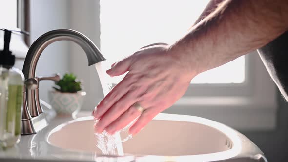 Man washing hands in bathroom sink