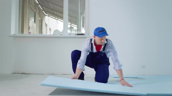 Man in Uniform Performing Construction Work Indoors and Placing Polystyrene Foam Insulation on Floor