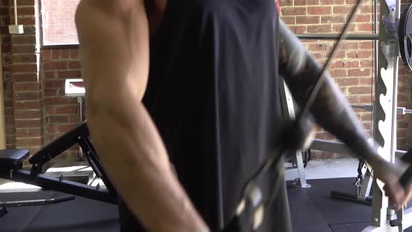 Muscly man in home gym exercising blurry doing cable lat pull