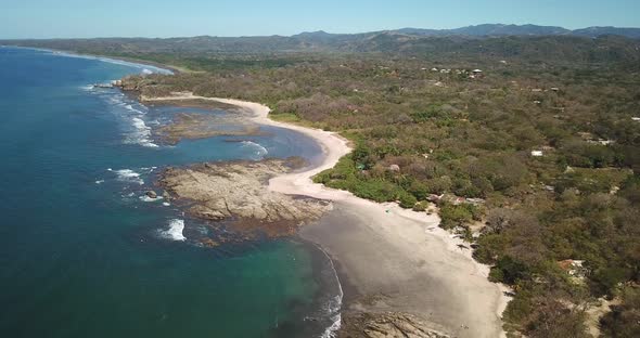 Aerial drone view of the beach, rocks and tide pools in Playa Palada, Guiones, Nosara, Costa Rica.