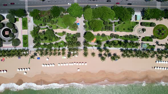 high altitude aerial top down view zooming onto the white beach umbrellas setup for tourists on the