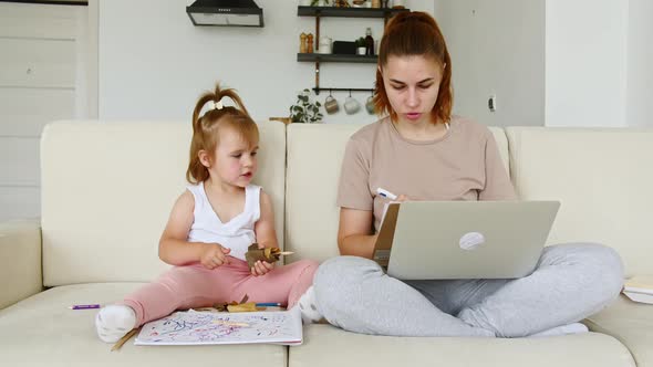 Mother Working From Home Having a Work Video Call and Child Playing Nearby