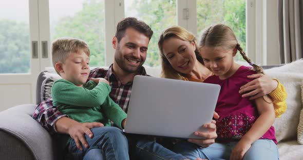 Family using laptop on the sofa in a comfortable home 4k