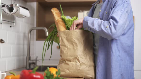 Female Hands Get Groceries Vegetables Baguette In The Kitchen, Returned From A Shopping Trip Bought