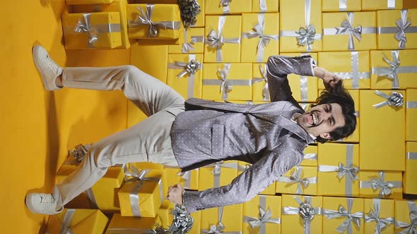 A Happy Caucasian Man in an Elegant Suit Dancing Merrily in a Room Full of Gift Boxes