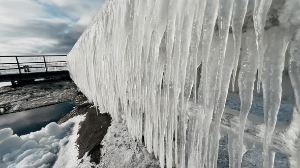 Huge Scary Icicles Hanging From Metal Railing on Sunny Winter Day