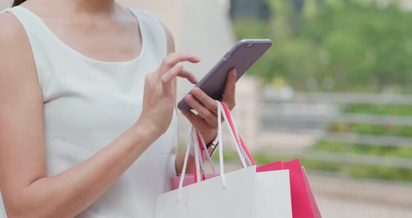 Woman use of smart phone and holding shopping bag