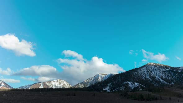 Snowy mountain range with rolling clouds and blue sky