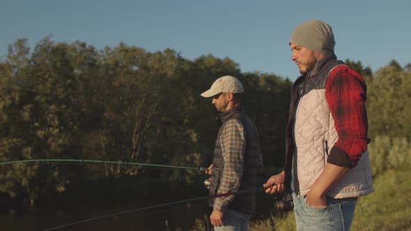 Fishermen friends with a spinning rod catching fish on a river.