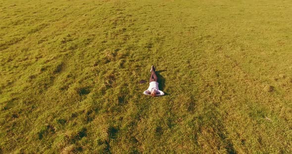 Low Orbital Flight Around Man on Green Grass with Notebook Pad at Yellow Rural Field