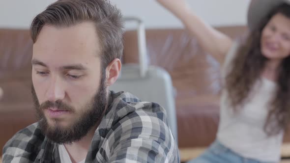 Portrait of an Offended Bearded Man Sitting in the Foreground While His Happy Wife