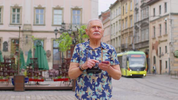 Elderly Stylish Tourist Man Looking for Way Find Route Using Smartphone in Old Town Lviv Ukraine