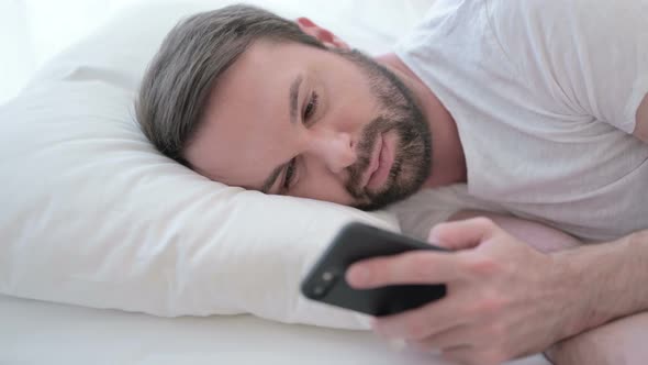 Close Up of Beard Young Man Using Smartphone in Bed