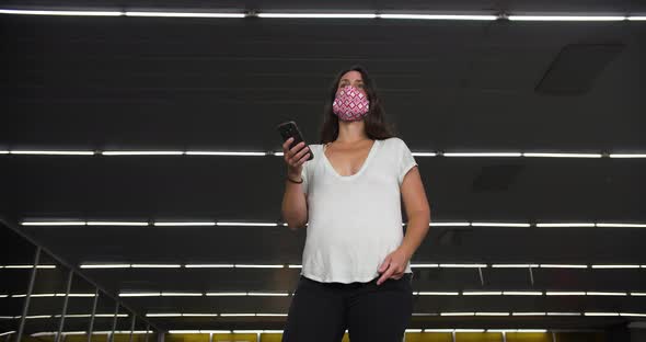 Woman Standing at Metro with Mask Using Phone