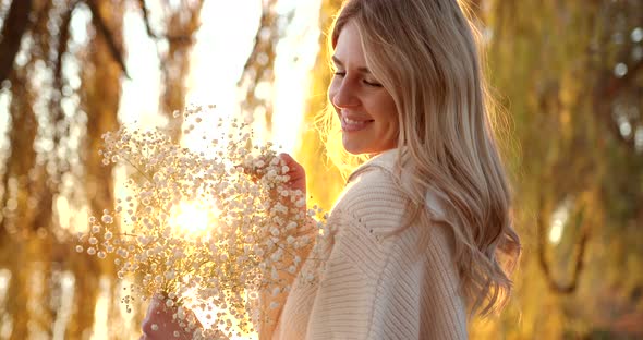 Happy Blonde Girl Basks in the Rays of the Evening Sun in the Autumn Park