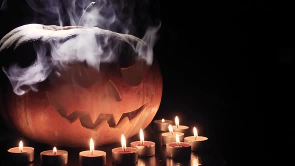 Halloween Pumpkin Head Jack Lantern with Burning Candles Over Black Background