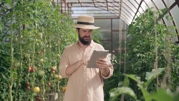 Portrait of Satisfied Male Farmer Leaving Feedback Online for Fertilizer Standing in Greenhouse with