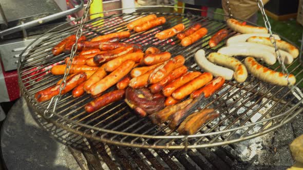 Adding charcoal to the grill. Bratwurst roasting on barbecue grill. BBQ grilling frankfurt beef