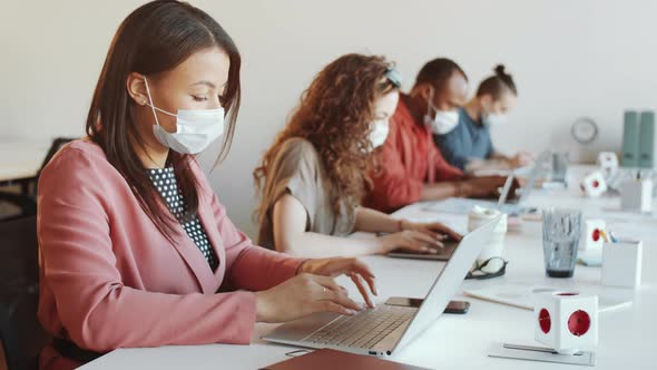 Woman in Face Mask Using Laptop at Office Desk during Workday