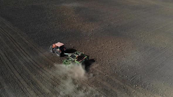 Orange Tractor Plows the Field. Aerial View. 