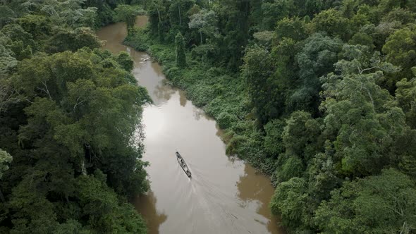 Aerial View Of Amazon Rainforest River With Boat Sailing.