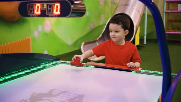 A Child Plays Air Hockey in an Entertainment Center