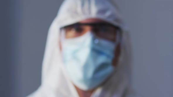 Portrait of caucasian male medical worker wearing protective clothing with mask and safety glasses