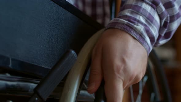 Closeup of Hand Disabled Person Man Turning the Wheel of Wheelchair