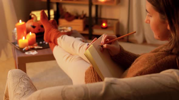 Woman Writing To Diary at Home on Halloween