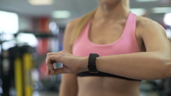 Fit Woman Clearing Indicators of Health Bracelet Before Starting Workout in Gym