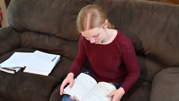 high school student, Madelyn, studies from a textbook, looks up at the camera with a huge smile