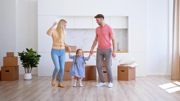 Happy family parents and preschooler daughter new apartment owners jump