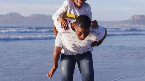 African american father giving a piggyback ride to his son at the beach