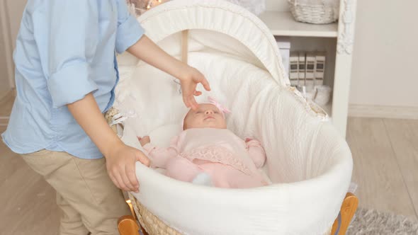 Little brother kiss her newborn sister at bed alt