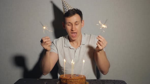 Close Up of Young Man with Cake and a Candles Holding the Sparkler