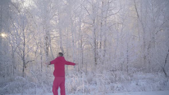 A Man Walks Through a Winter Forest with Snow Covered Trees on a Beautiful Frosty Morning