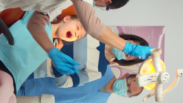 Vertical Video Dentist Technician with Gloves Explaining the Process to Kid Patient