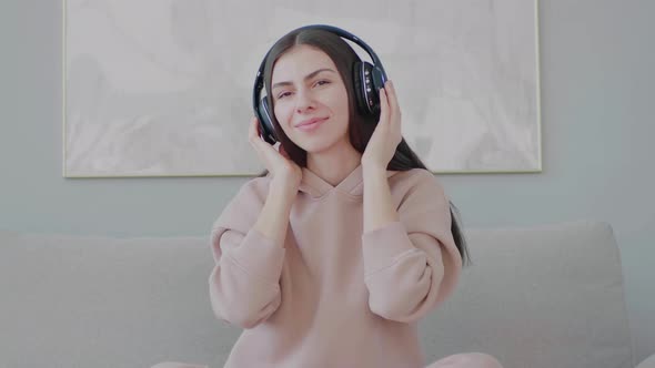 Young funny woman with headphones listening to music, singing along and dancing.