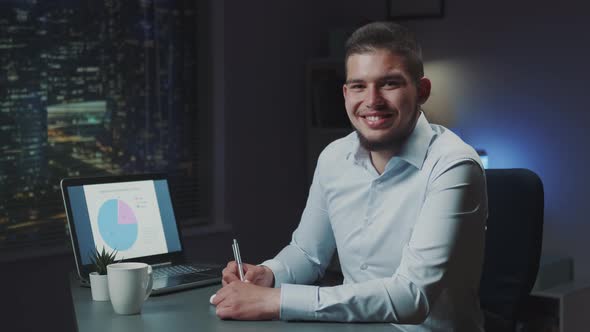 Handsome Young Business Working in Office and Smiling to the Camera in the Evening