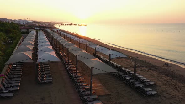 Scenic View of Sandy Beach with Sunbeds at Sunset.